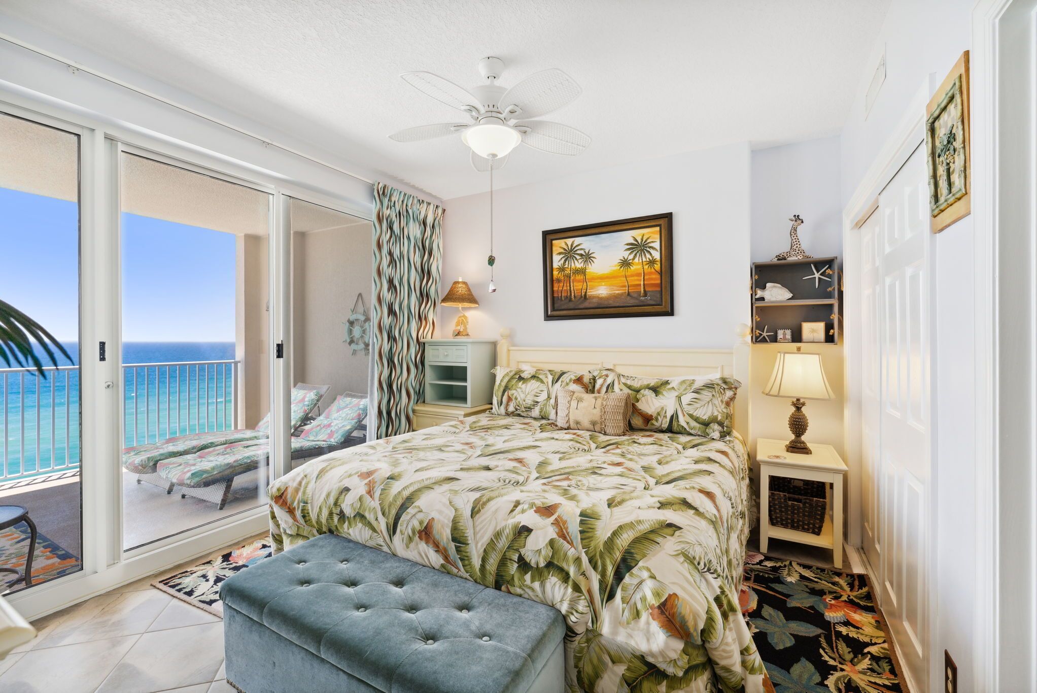 Ein Schlafzimmer mit Bett, Deckenventilator, Meerblick und einem Balkon mit Stuhl.