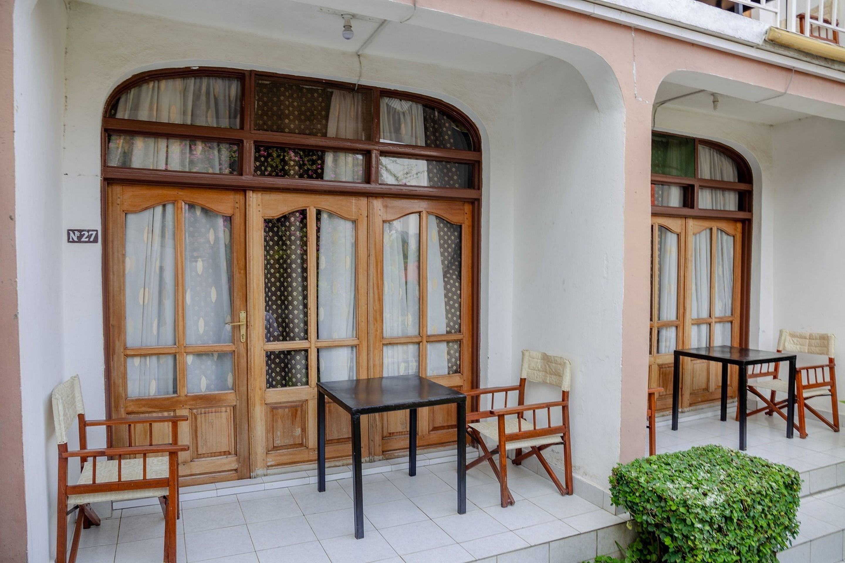 A building with large wooden doors, a small table, and two chairs outside.
