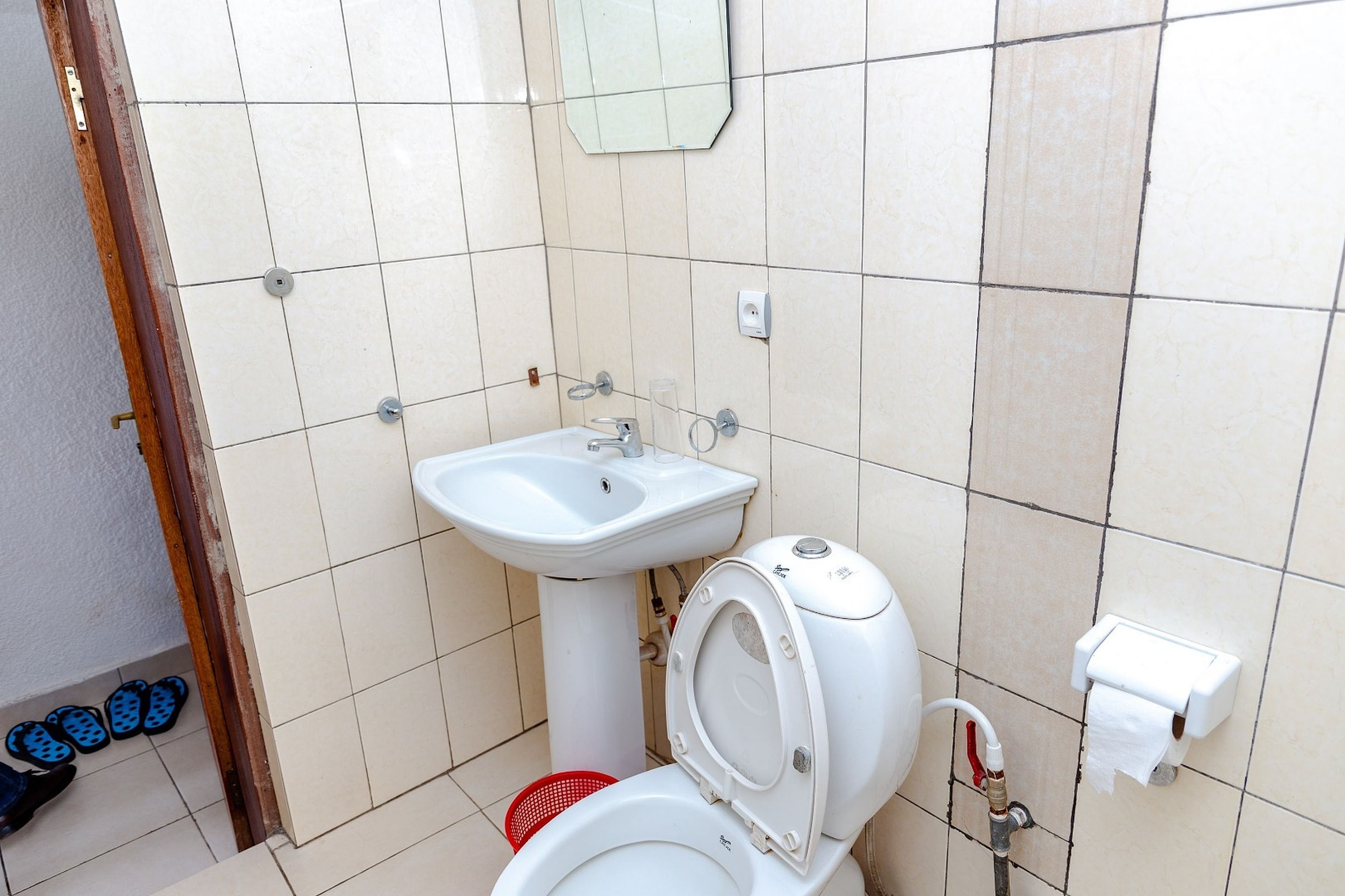 A small bathroom with a toilet, sink, and a mirror.
