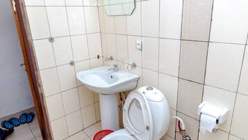 A small bathroom with a toilet, sink, and a mirror.