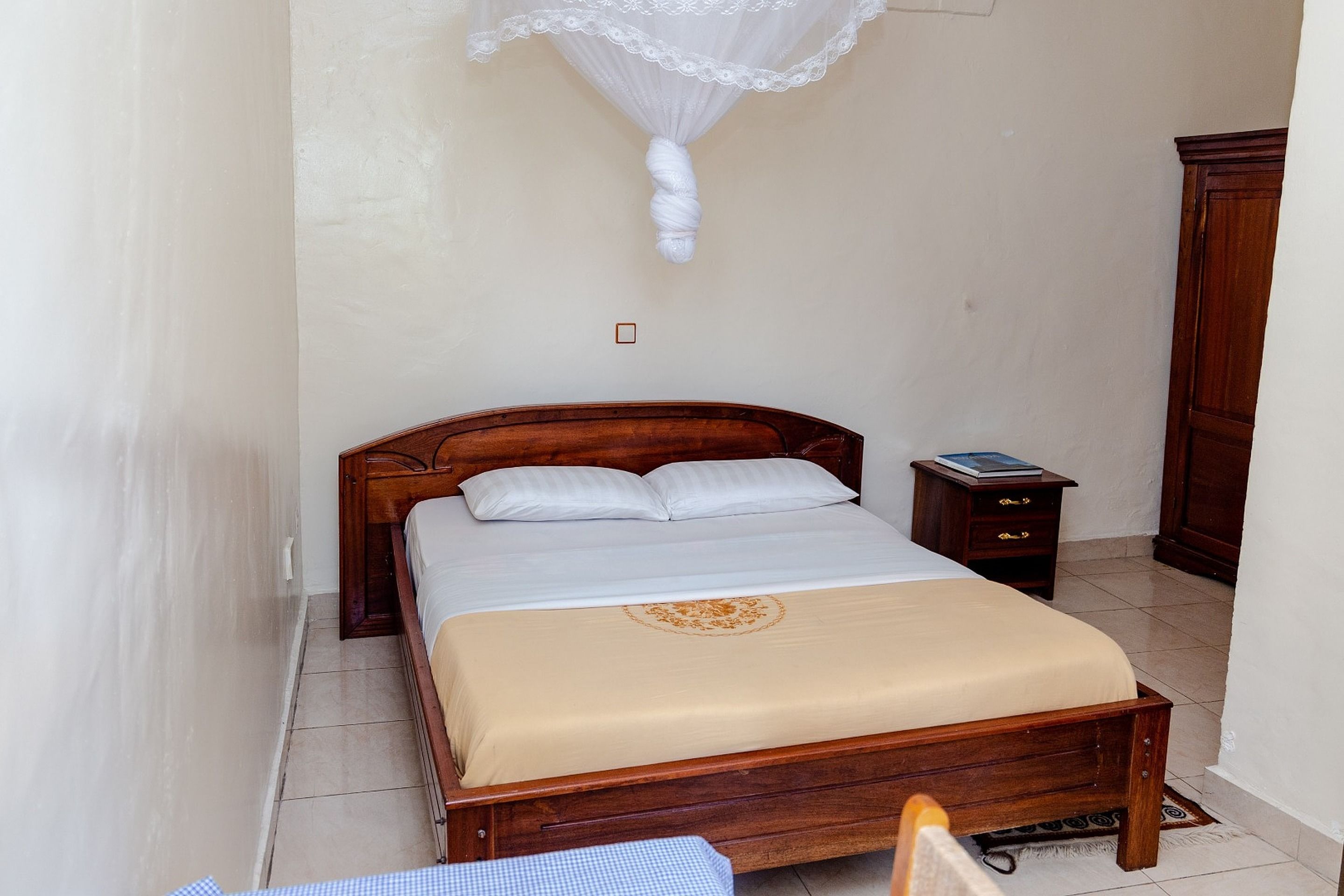 A bedroom with a wooden bed, a bedside table, a nightstand, and a wardrobe.