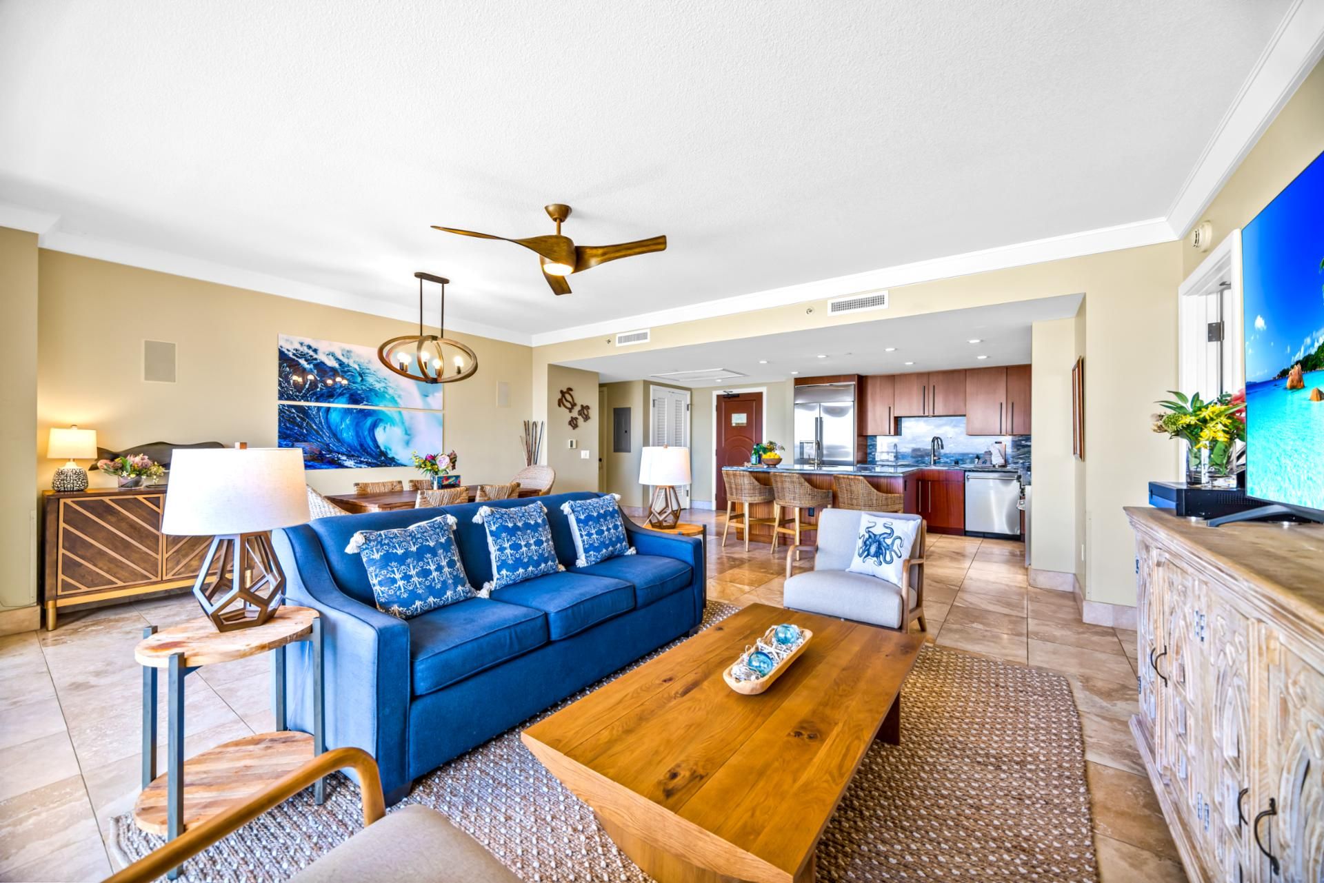 A spacious living room with a blue sofa, wooden coffee table, and a dining area with a large painting.