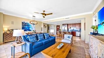 A spacious living room with a blue sofa, wooden coffee table, and a dining area with a large painting.