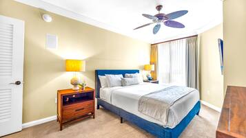 A hotel room with a bed, nightstands, a ceiling fan, and a window with curtains.