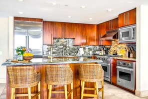 Uma cozinha moderna com uma ilha central, eletrodomésticos de aço inoxidável e armários de madeira.