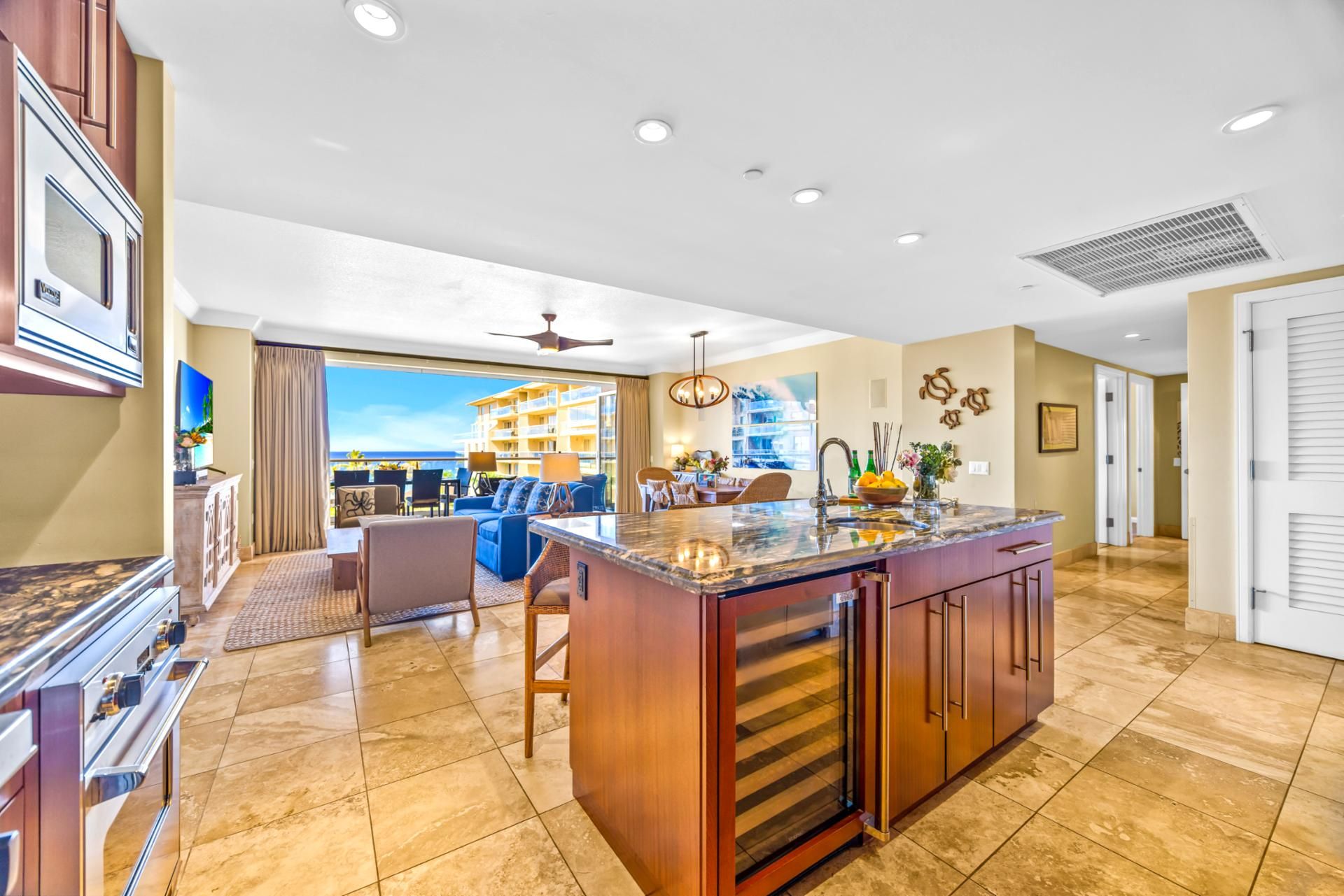 A spacious kitchen with a large island, modern appliances, and a view to a balcony.