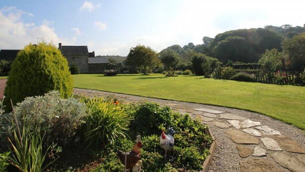 A well-maintained garden with a stone pathway, a variety of plants, and a large lawn. - Stone house near the sea with sauna and large garden (Baubigny)