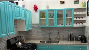 A kitchen with teal cabinets, a granite countertop, a stove, and a sink.