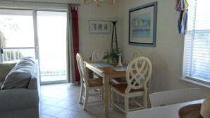 A dining area with a table, chairs, and a chandelier. There is a sofa and a window with blinds. - Reduced  rates  on 30A beach front condo. (Santa Rosa Beach)