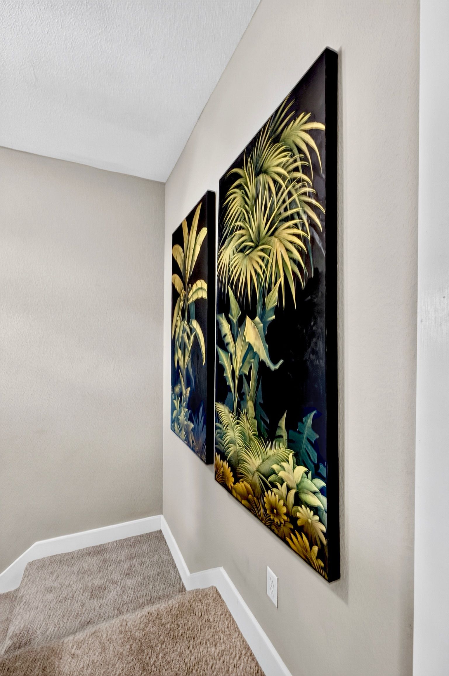 Un couloir orné de deux tableaux représentant des plantes tropicales, accrochés aux murs.
