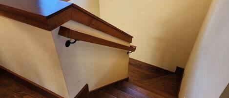 A corner of a room with a wooden counter and a wooden staircase.