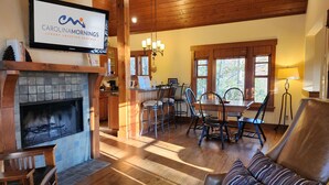 A cozy living area with a fireplace, wooden furniture, and a dining table with chairs.