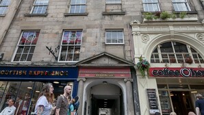 Ein Gebäude mit mehreren Geschäften im Erdgeschoss, darunter ein Café und ein Geschäft namens "Scottish Experience".