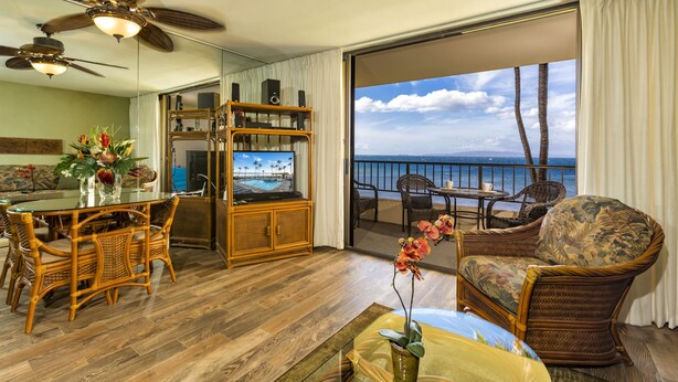 A spacious living area with a balcony, a dining set, and a television.