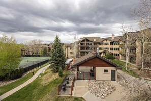 A residential building with a tennis court, a wooden deck, and a small shed.