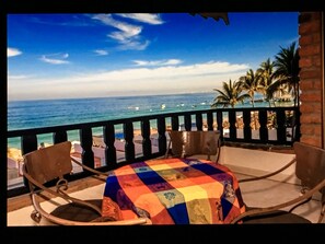 A balcony with a view of the ocean and palm trees.
