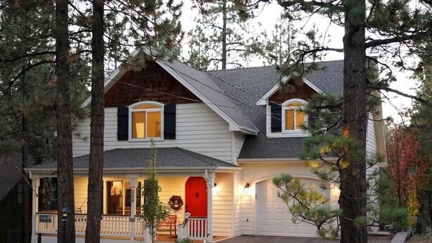 A two-story house with a porch, a red door, and a garage.
