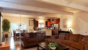 A spacious living area with a sofa set, a coffee table, and a dining table with chairs.