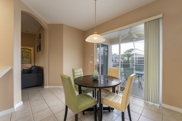 A dining area with a round table, four chairs, a vase, and a ceiling fan. - Golf Community/ Private Pool/ Near theme parks (Davenport)