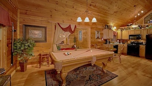 Une charmante cabane en bois dotée d’une table de billard, d’un coin repas et d’une cuisine.