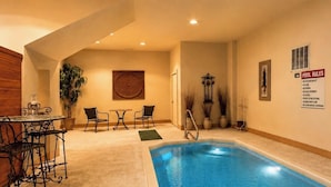 Un espace piscine comprenant un jacuzzi, des sièges et un panneau indiquant les règles à respecter.