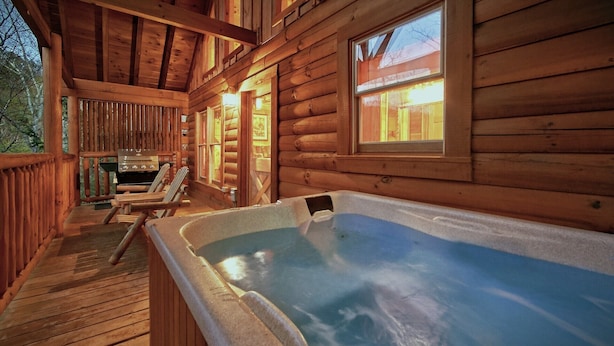 Une cabane en bois avec un jacuzzi, une terrasse et une cheminée.
