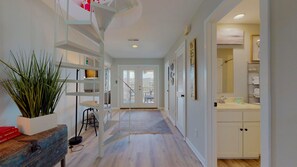 Stunning interior with a central staircase, bookshelf, and kitchen area with white cabinetry.