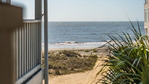 Uitzicht op de kust vanaf een raam, met zee, strand en begroeiing.