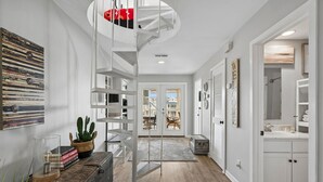 Een modern interieur met een spiltrap, een boekenkast, een cactuss en uitzicht naar buiten.