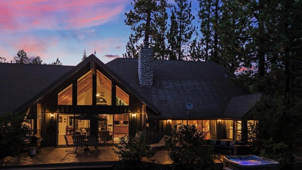 Une grande maison moderne, dotée d’une lucarne imposante, d’un jacuzzi et d’un patio bien éclairé.