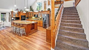 Une cuisine spacieuse avec des meubles en bois, un grand îlot central et un réfrigérateur en acier inoxydable.
