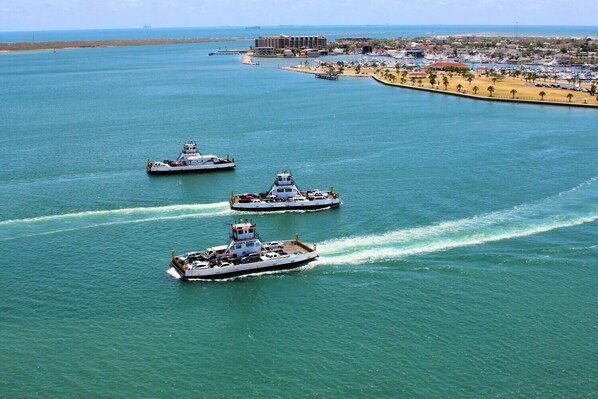 Three large boats on a calm sea with a coastal cityscape in the background.