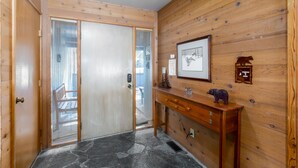 Ein Holzinnenraum mit einer Schiebetür, einem kleinen Holztisch und einem gerahmten Bild an der Wand.