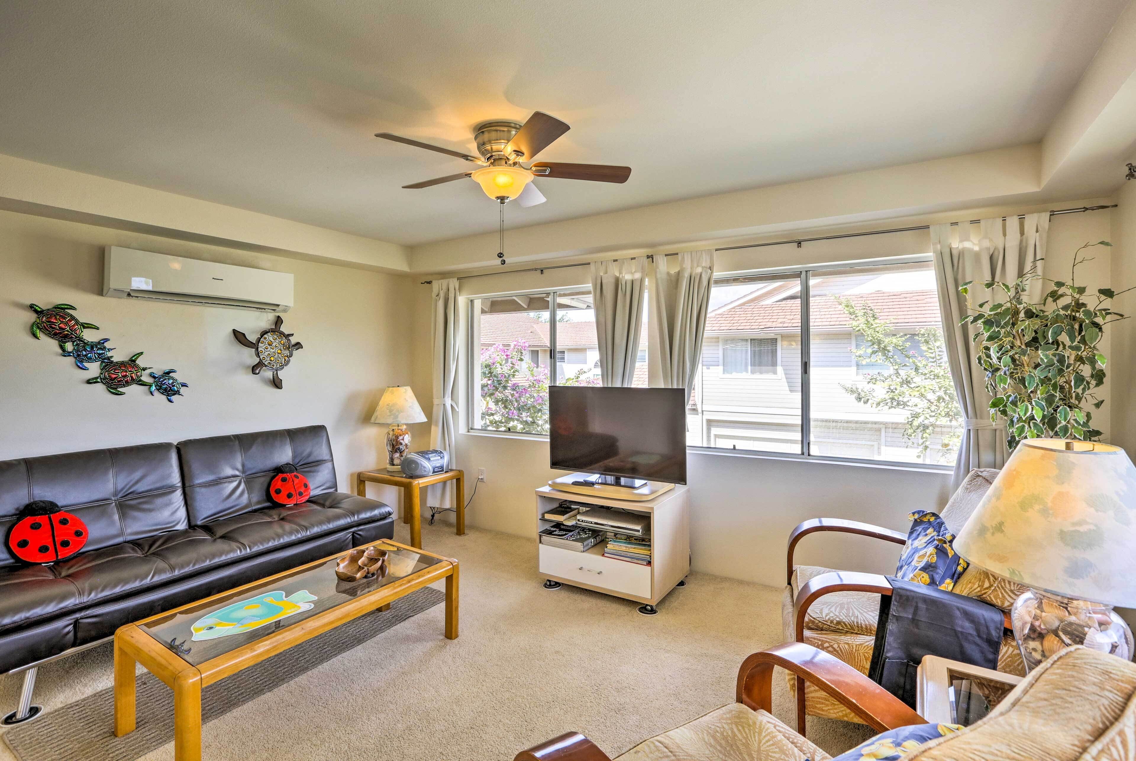 A living room with a sofa, coffee table, TV stand, and a ceiling fan.