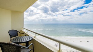 Un balcon avec une table et des chaises donnant sur une plage.