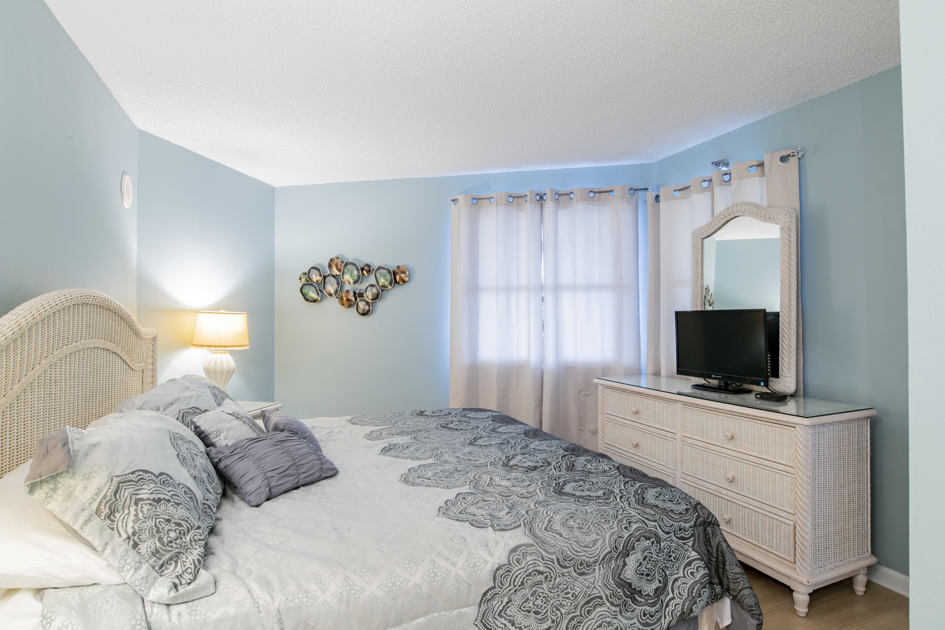 A bedroom with a bed, dresser, television, and decorative wall art.