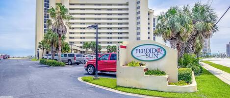 A hotel sign with a large building in the background.