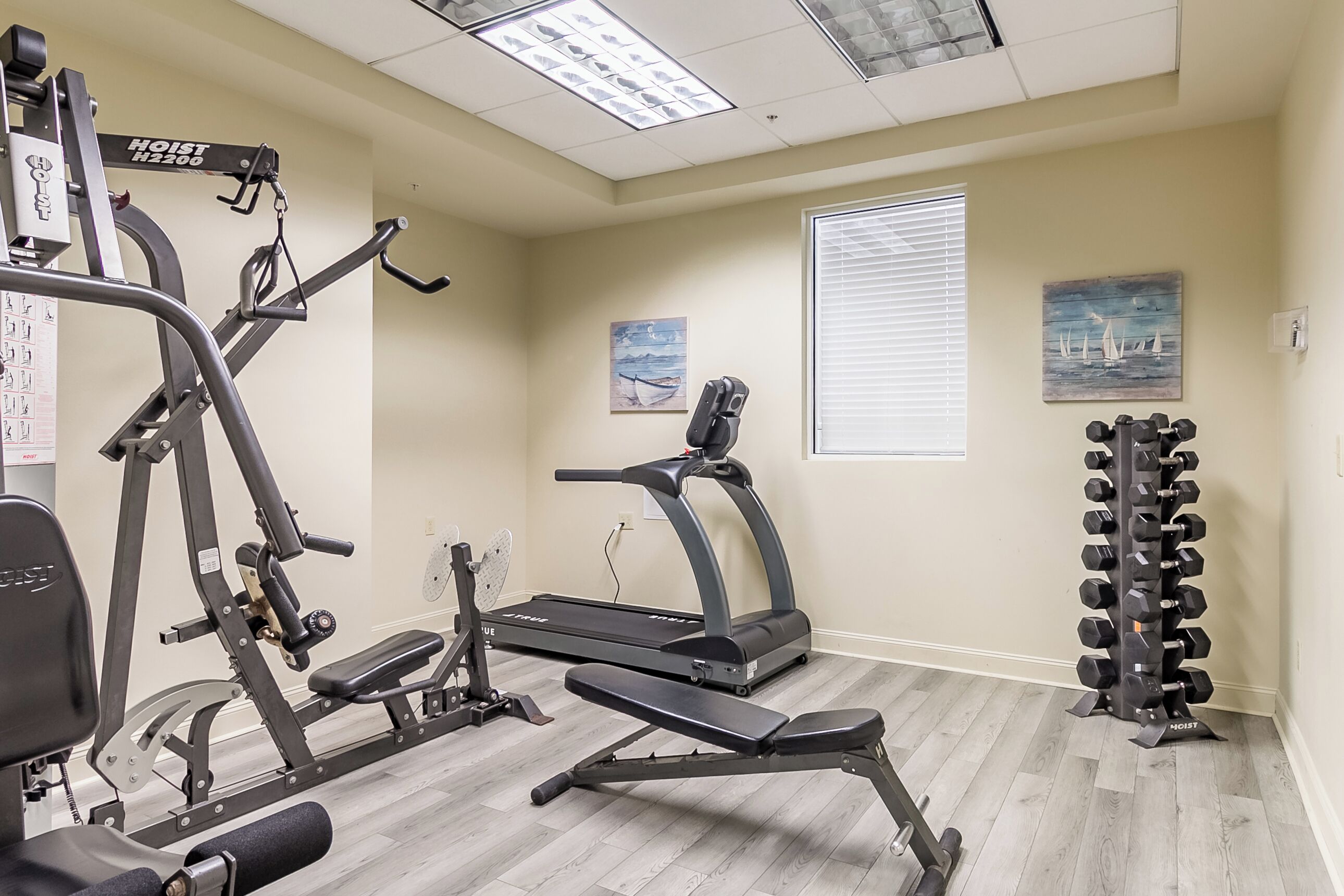 Un gimnasio con equipo de ejercicio, una cinta de correr y un estante con mancuernas.
