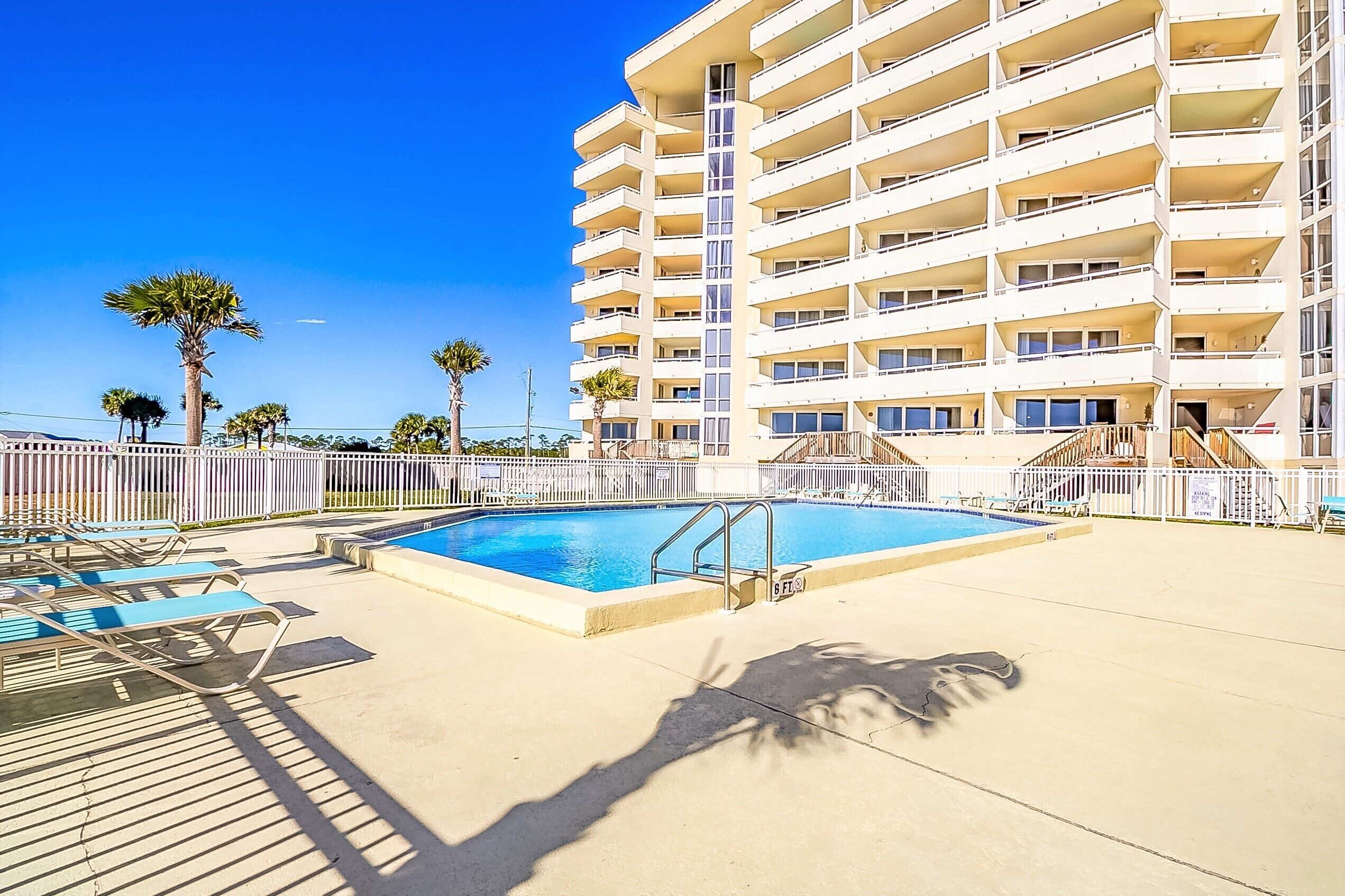Un hôtel doté d’une piscine, de nombreux balcons et de palmiers.