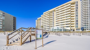 Un hôtel situé en bord de mer, doté d’un escalier en bois menant à une zone abritée, le tout entouré d’immeubles de grande hauteur.