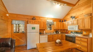 A cozy cabin-style kitchen with wooden cabinets, a refrigerator, a microwave, and a dining table. - ER307- Eagle's View- Great location- Close to town (Pigeon Forge)