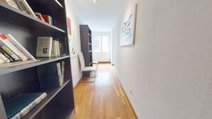 A hallway with bookshelves, a white chair, and a window. - jaquet 137m2  city center 2br 2bth (Colmar)