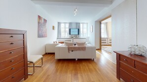A modern bedroom with a white bed, wooden dresser, and a television on a stand. - jaquet 137m2  city center 2br 2bth (Colmar)