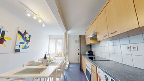 A modern kitchen with wooden cabinets, a stainless steel refrigerator, and a tiled backsplash. - jaquet 137m2  city center 2br 2bth (Colmar)