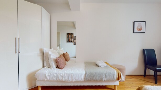 A bedroom with a bed, a chair, a wardrobe, and a mirror. - jaquet 137m2  city center 2br 2bth (Colmar)