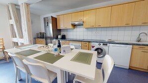 A modern kitchen with wooden cabinets, a stainless steel refrigerator, an LG washing machine, and a dining area with white chairs and a table. - jaquet 137m2  city center 2br 2bth (Colmar)