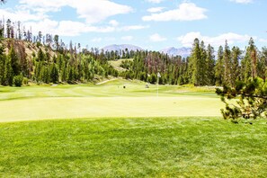 A golf course with a clear sky, green grass, and pine trees. - River Run Condo w/ Shared Hot Tub, Pool & Sauna, Mountain Views from Balcony! (Keystone)