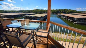 A deck with outdoor seating and a view of a marina with boats docked. - Comfy Ledges Lakefront Condo--quiet cove, boat slip included! (Osage Beach)