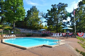 Una piscina con una recinzione decorata con bandiere, poltrone prendisole e una bandiera americana.