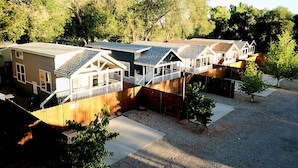 A row of single-story houses with attached porches, a gravel driveway, and a wooden fence.
